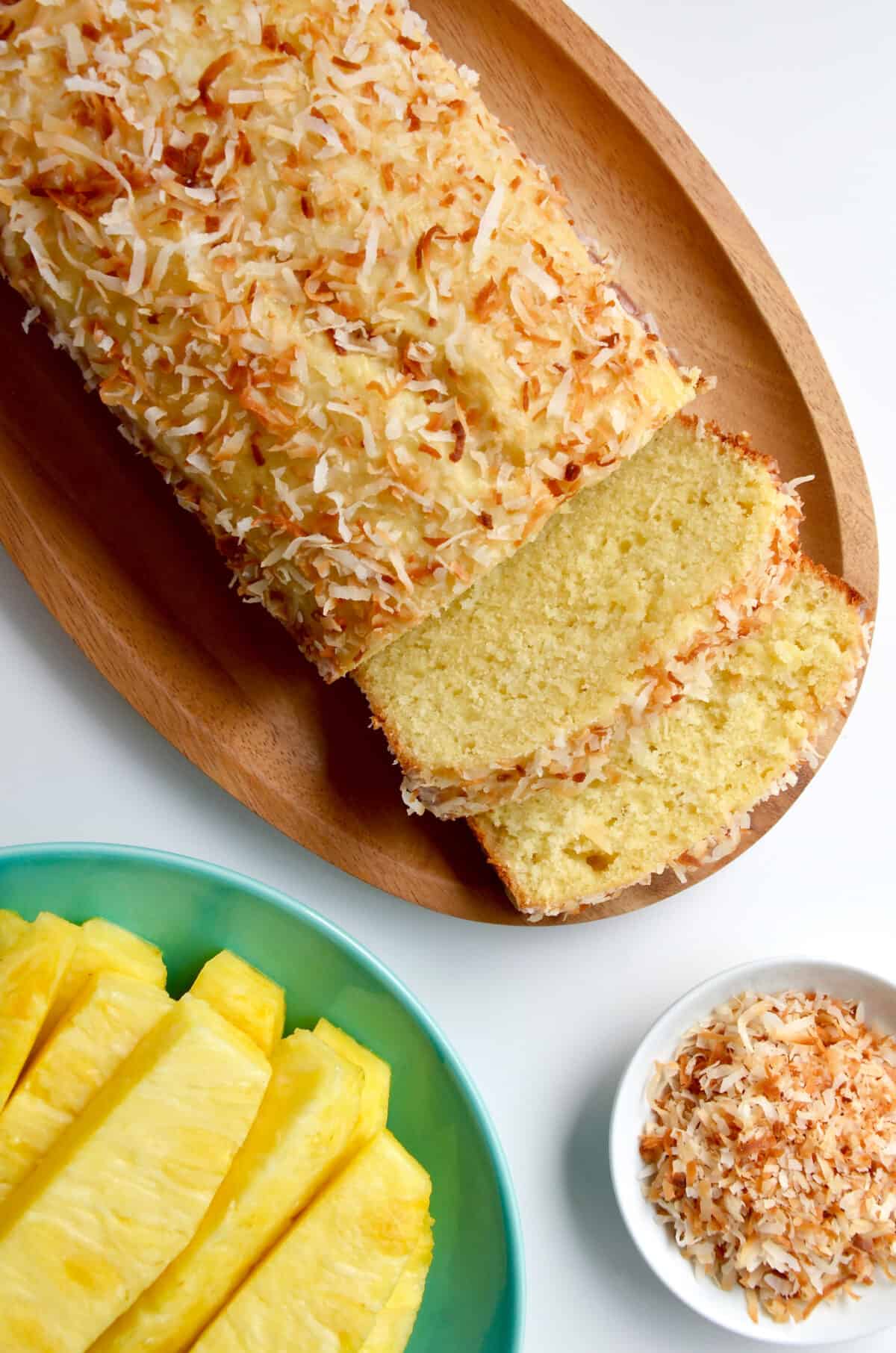 Glazed pineapple coconut bread next to a plate with slices of pineapple.