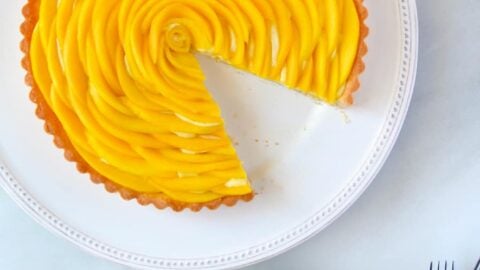 Sliced mango tart with vanilla bean pastry cream next to two forks