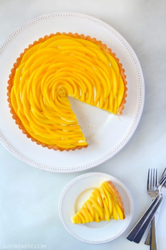 Sliced mango tart with vanilla bean pastry cream next to two forks 
