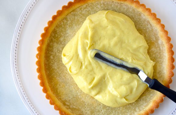 Offset spatula spreading pastry cream into tart shell