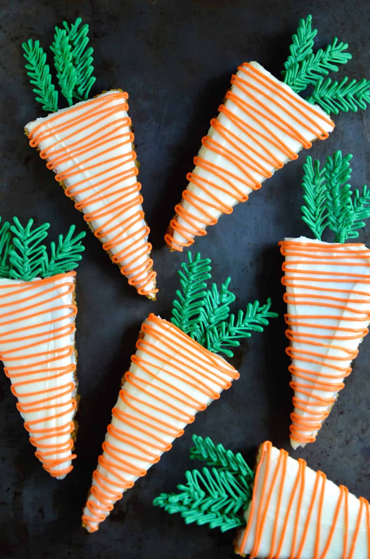 Pineapple carrot cake with cream cheese frosting cut into triangles and drizzled with orange candy melts.