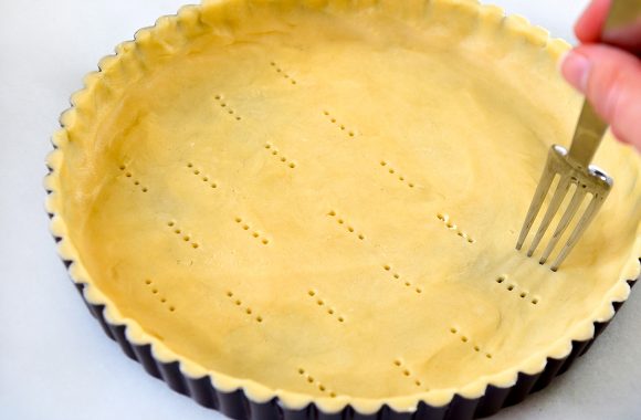 Fork pricking holes all over unbaked crust
