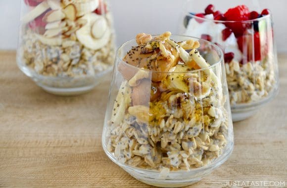 Three clear glasses containing overnight oats with various toppings