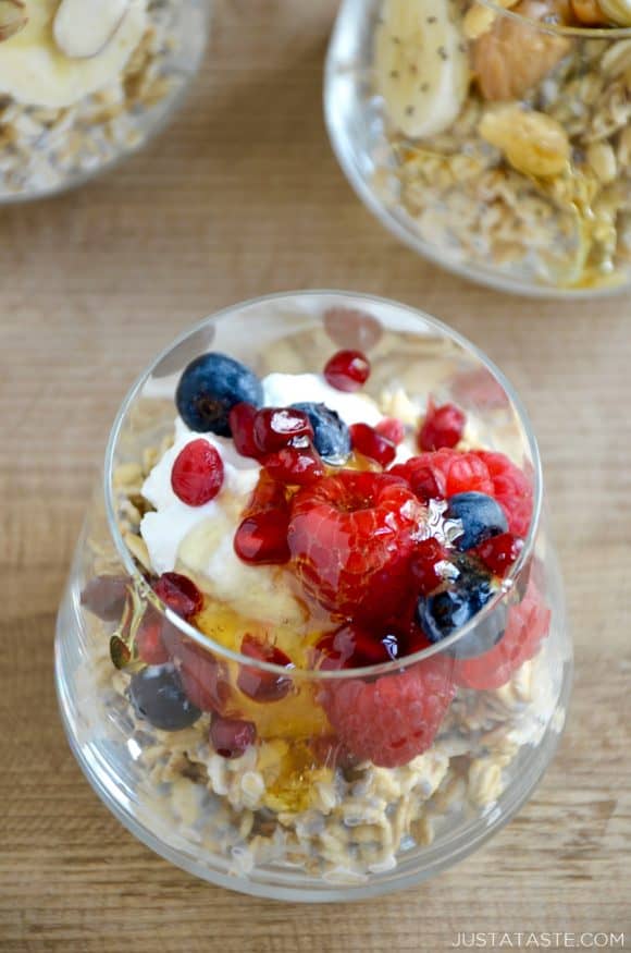 A clear glass containing overnight oats topped with yogurt, raspberries and blueberries