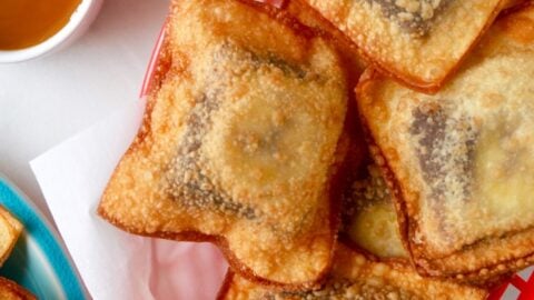 Banana Chocolate Wonton Poppers in a red food basket next to a small bowl filled with caramel sauce