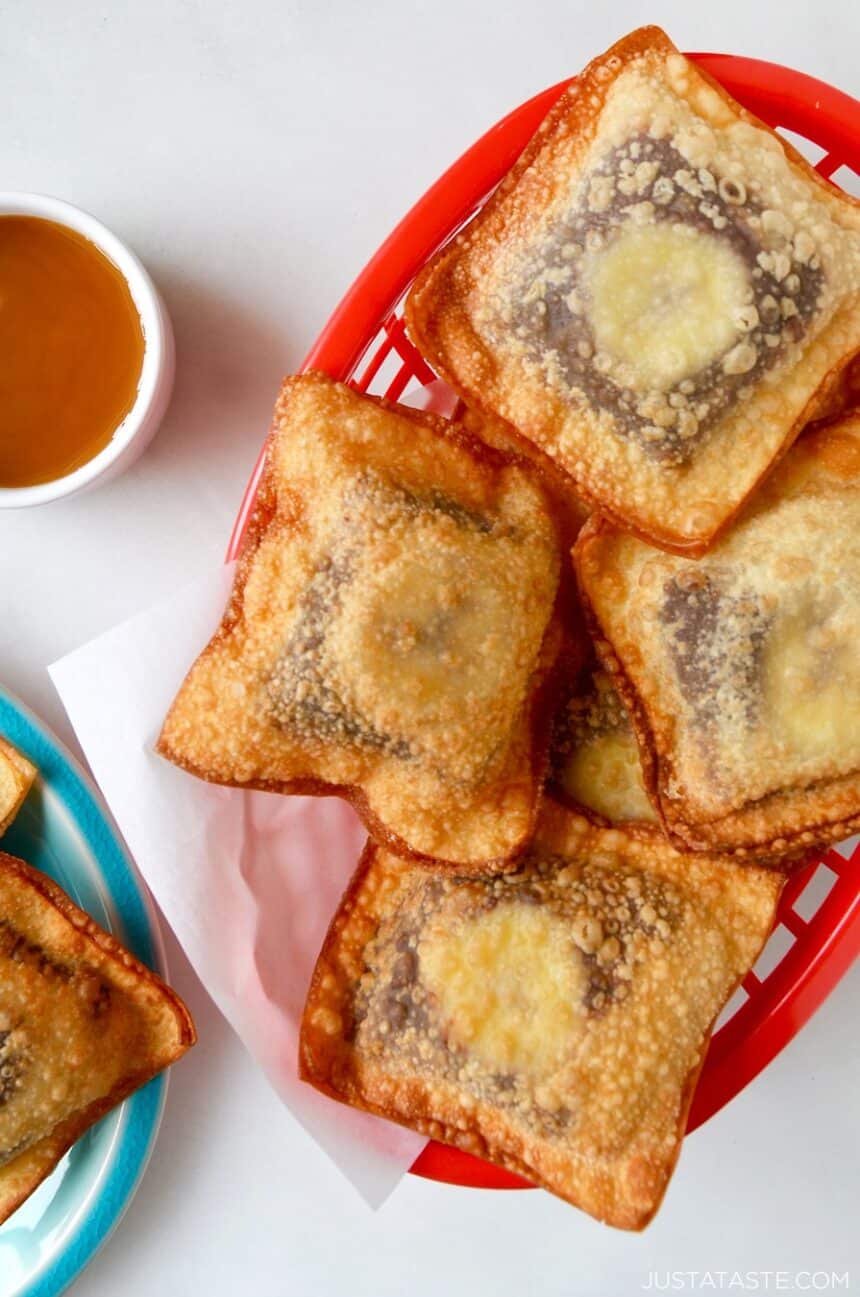 Banana Chocolate Wonton Poppers in a red food basket next to a small bowl filled with caramel sauce