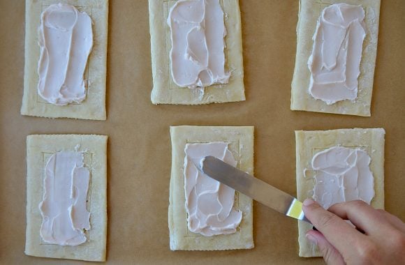 Strawberry cream cheese jam being spread onto puff pastry