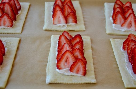 Sliced strawberries in rows on top of cream cheese pastry