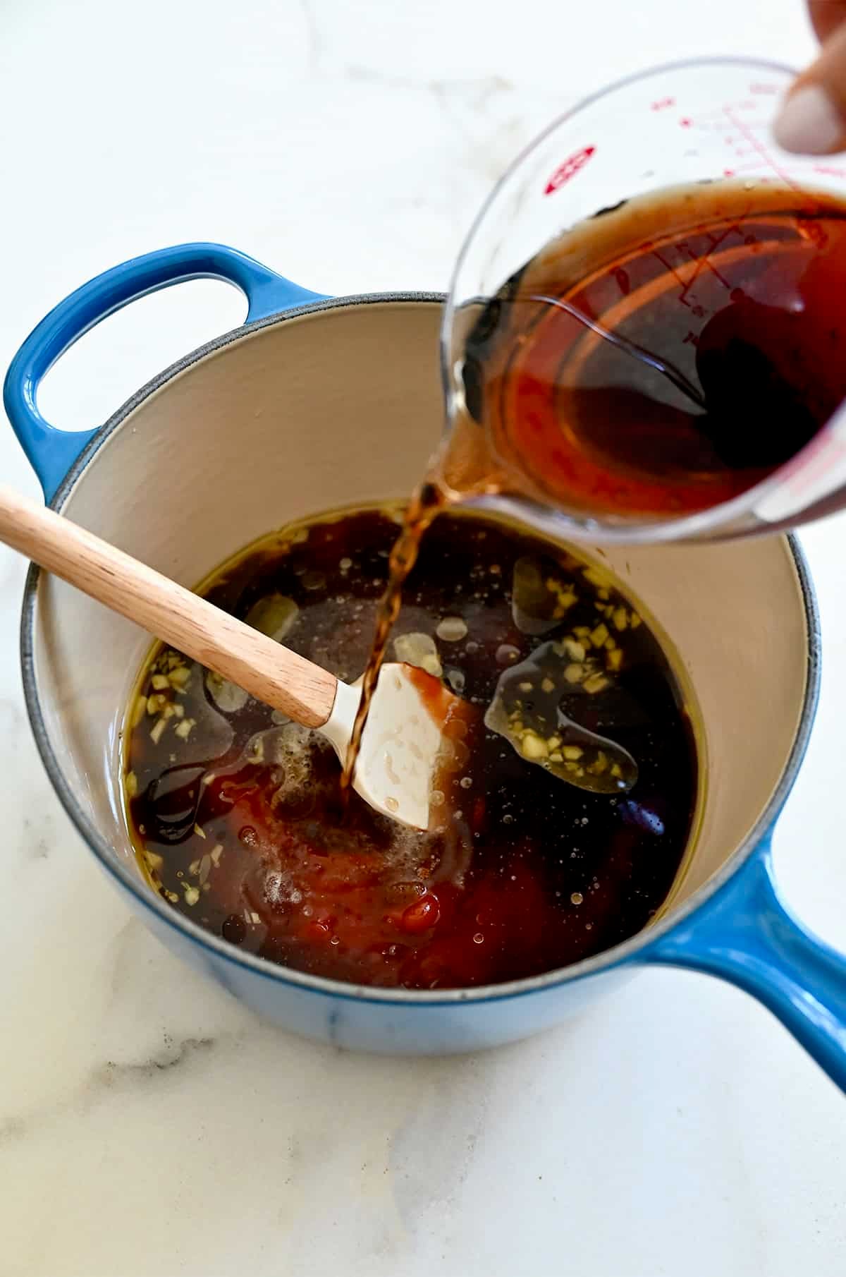 Adding ingredients to a medium saucepan to make BBQ sauce.