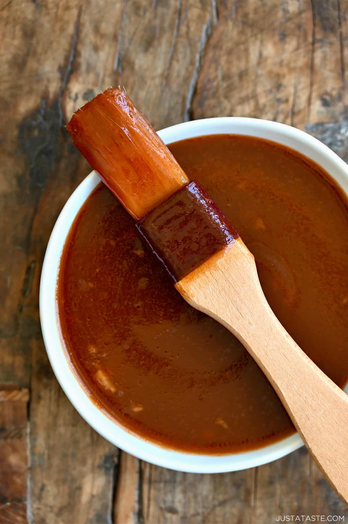 Homemade BBQ sauce in a bowl with a meat basting brush resting across it.