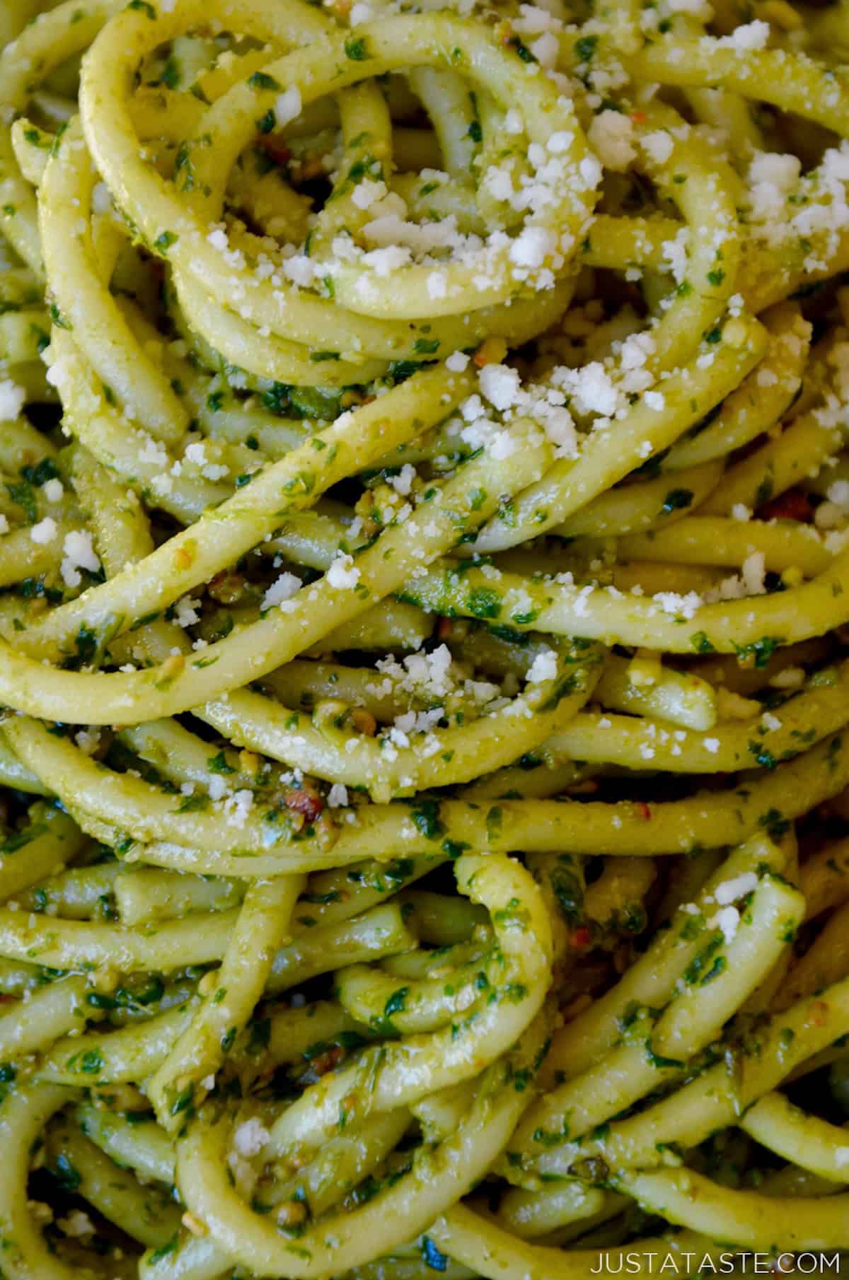 Spaghetti coated in pesto and grated Parmesan cheese.