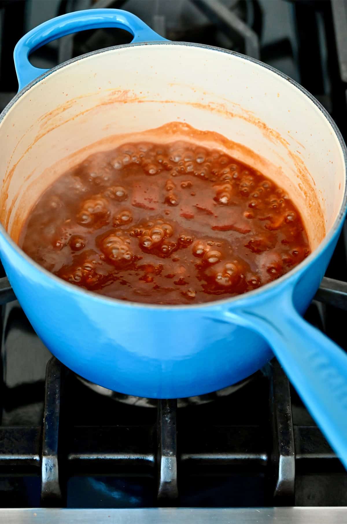 Homemade barbecue sauce simmering in a saucepan on the stove.