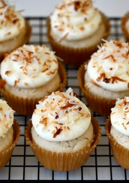 Coconut cupcakes with cream cheese frosting and toasted coconut flakes.
