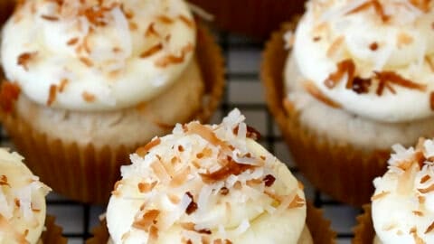 Coconut cupcakes with cream cheese frosting and toasted coconut flakes.