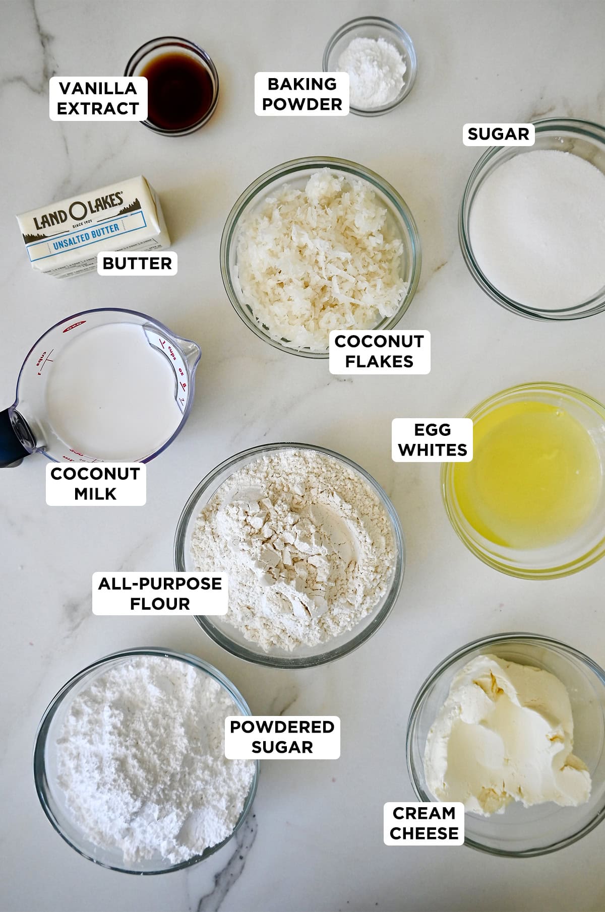 Ingredients needed to make coconut cupcakes in various sizes of glass bowls.