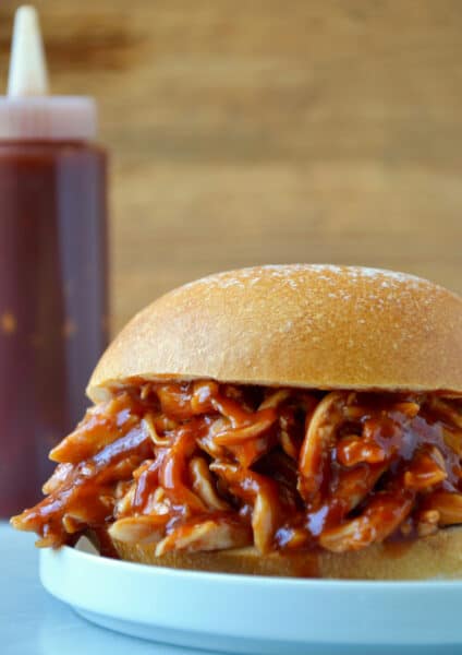 Pulled pork doused in Easy Homemade Root Beer Barbecue Sauce sandwiched between two hamburger bun halves.