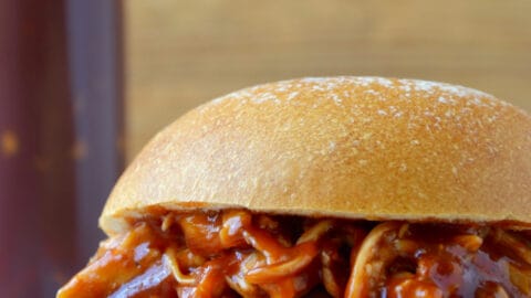 Pulled pork doused in Easy Homemade Root Beer Barbecue Sauce sandwiched between two hamburger bun halves.