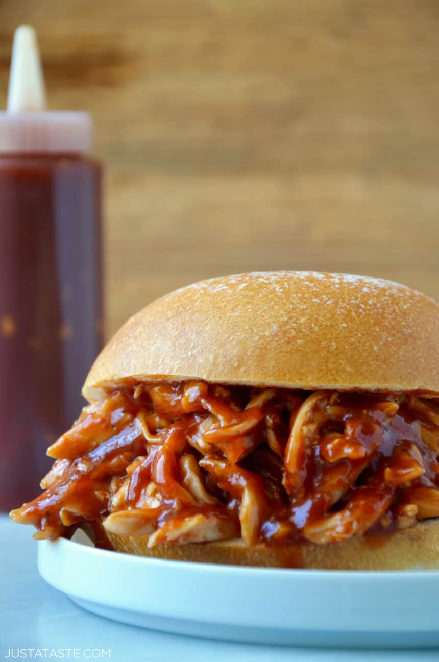 Pulled pork doused in Easy Homemade Root Beer Barbecue Sauce sandwiched between two hamburger bun halves.