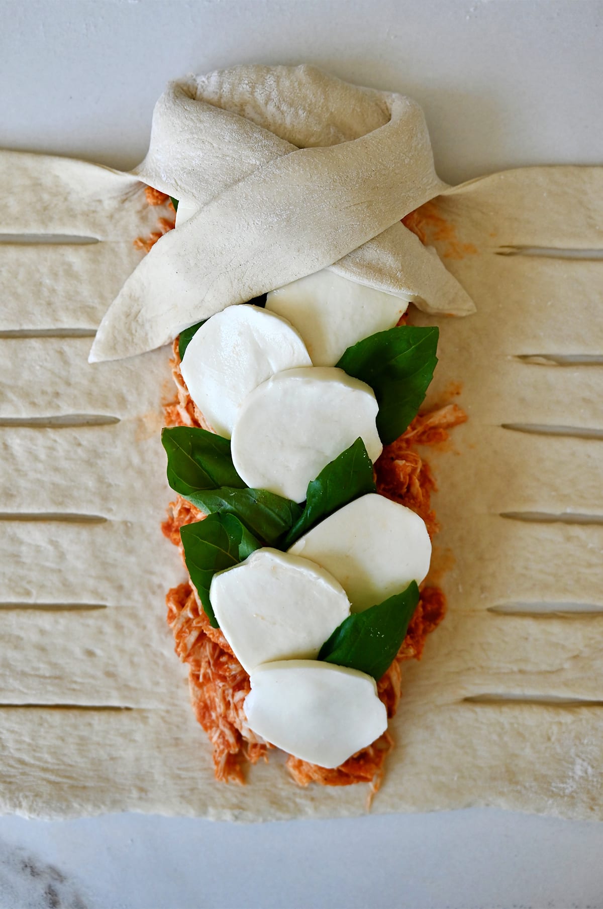 The beginning step to braiding pizza dough for a Stromboli - folding the top pizza dough over the filling. 