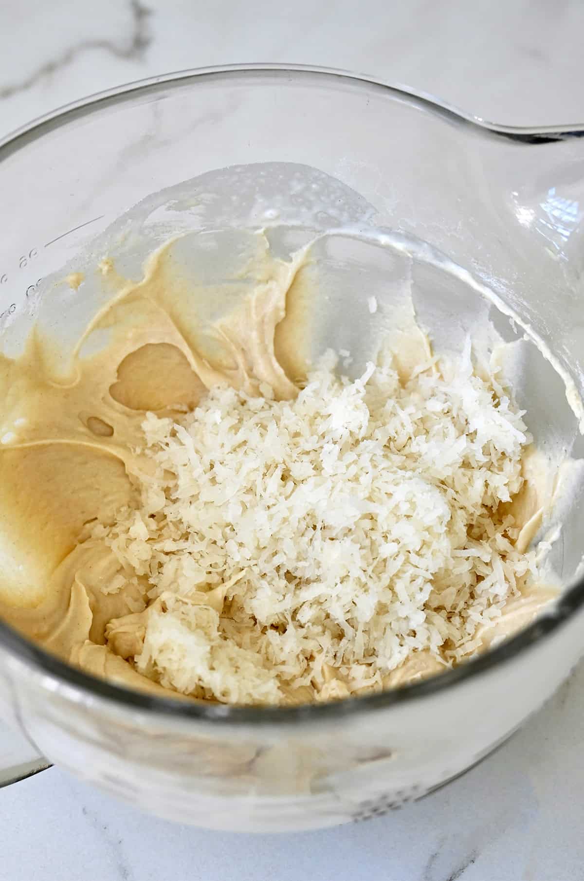 Folding in sweetened flaked coconut into coconut cupcake batter.
