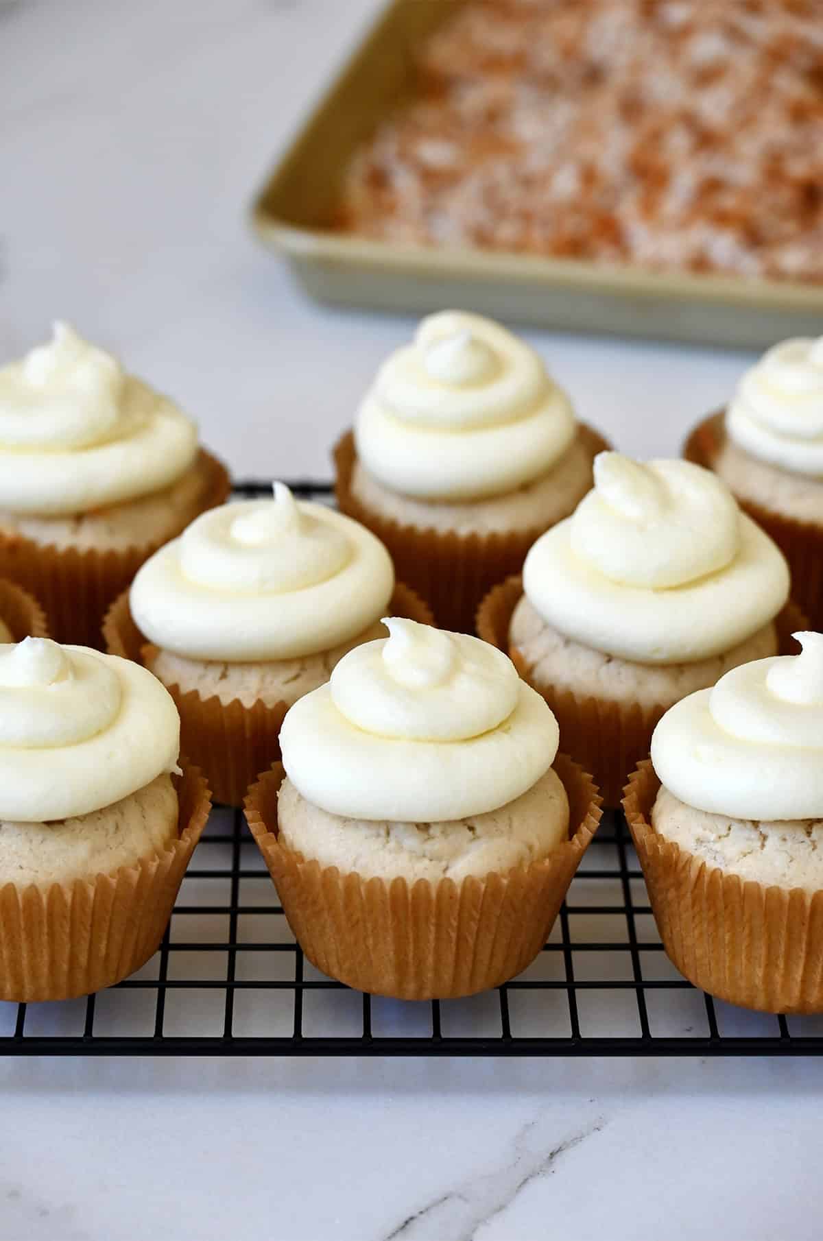 Fluffy coconut cupcakes topped with piped cream cheese frosting.