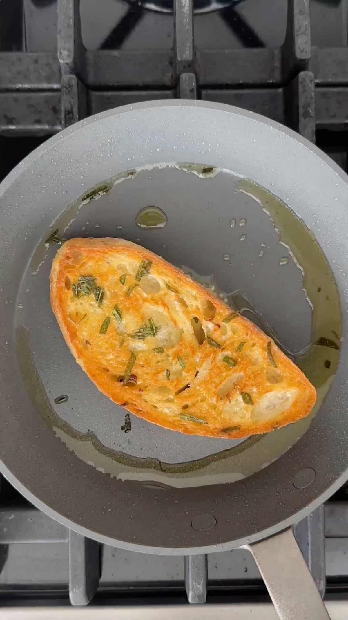 Toasted sourdough bread with herb olive oil in a skillet.