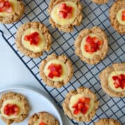 Top-down view of cheesecake cookies topped with chopped fresh strawberries on a wire cooling rack.