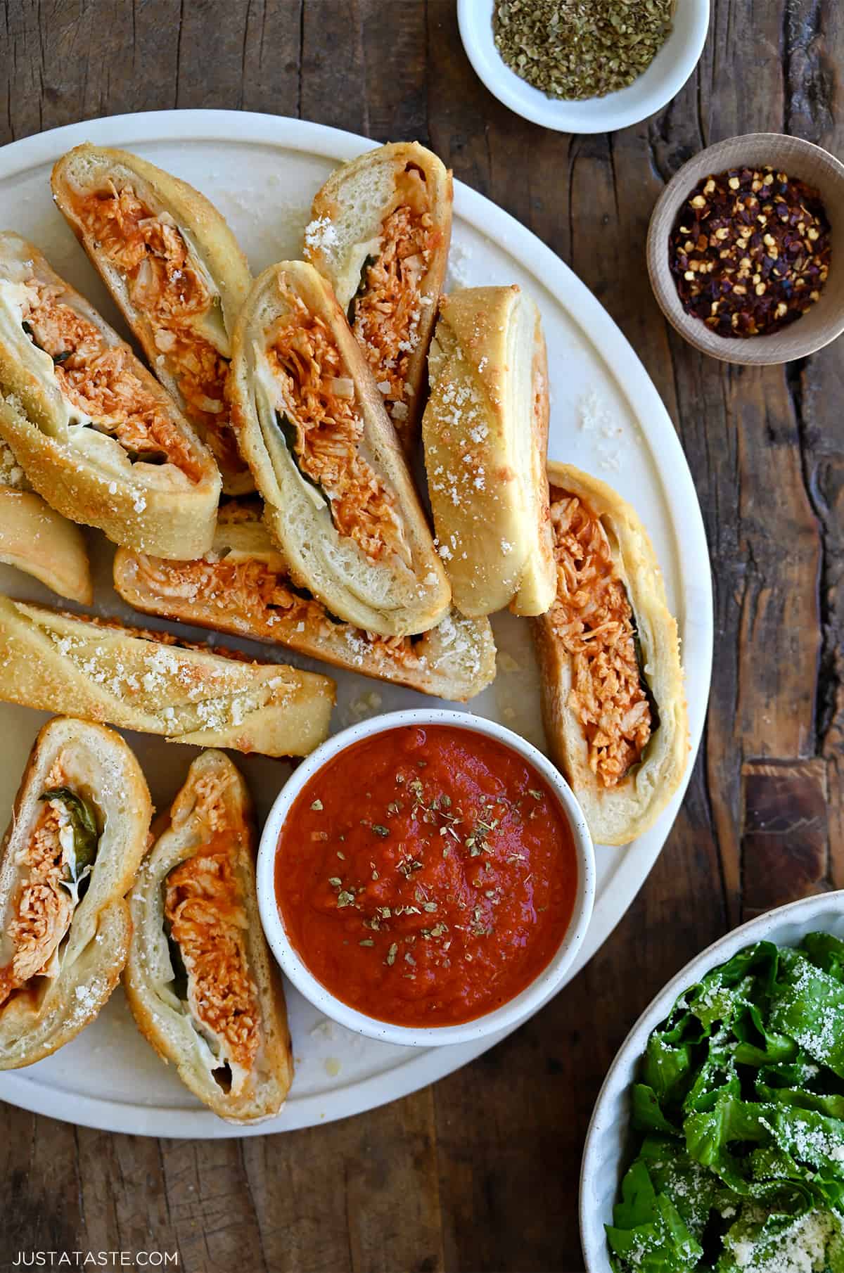 Slices of Stromboli on a round serving platter along with a small bowl containing marinara sauce.