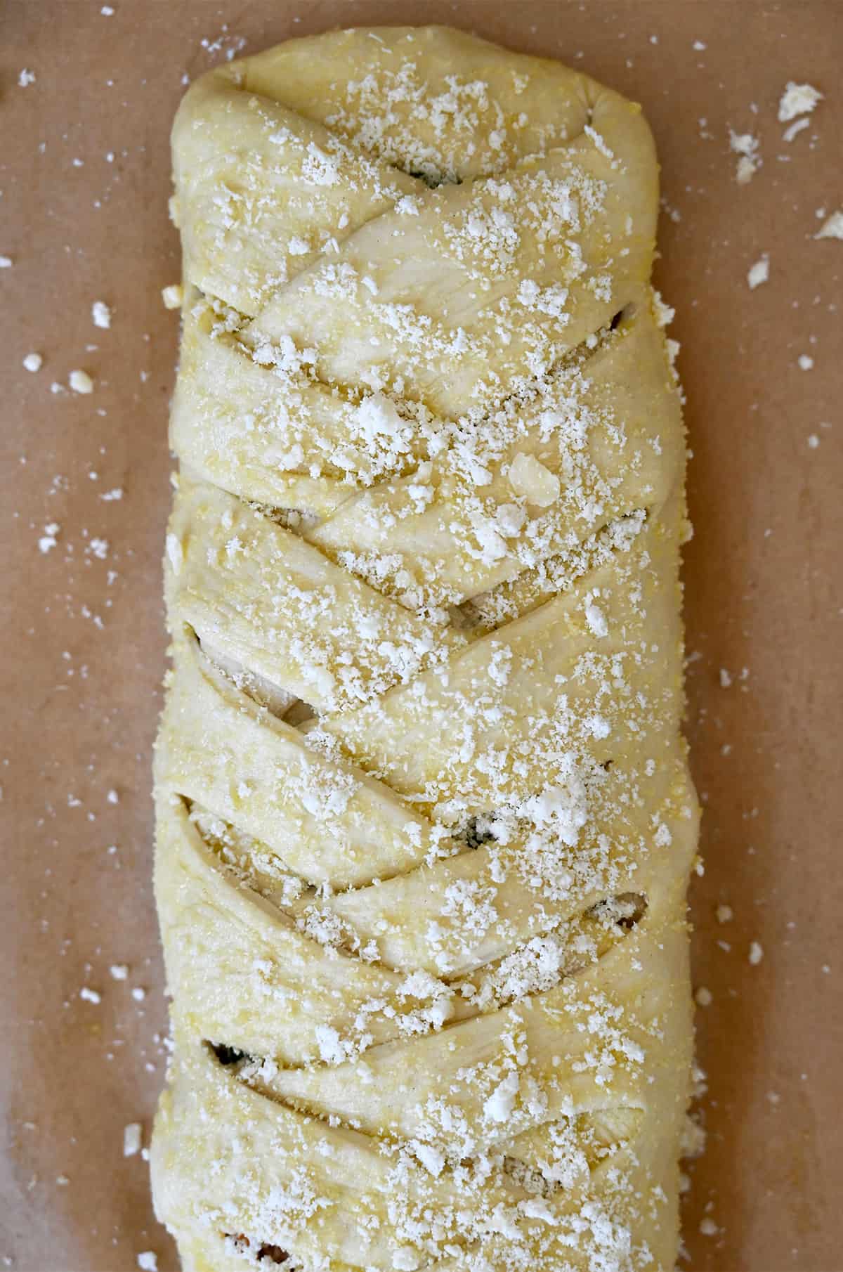 Unbaked Stromboli sprinkled with grated Parmesan cheese on a parchment paper-lined baking sheet.