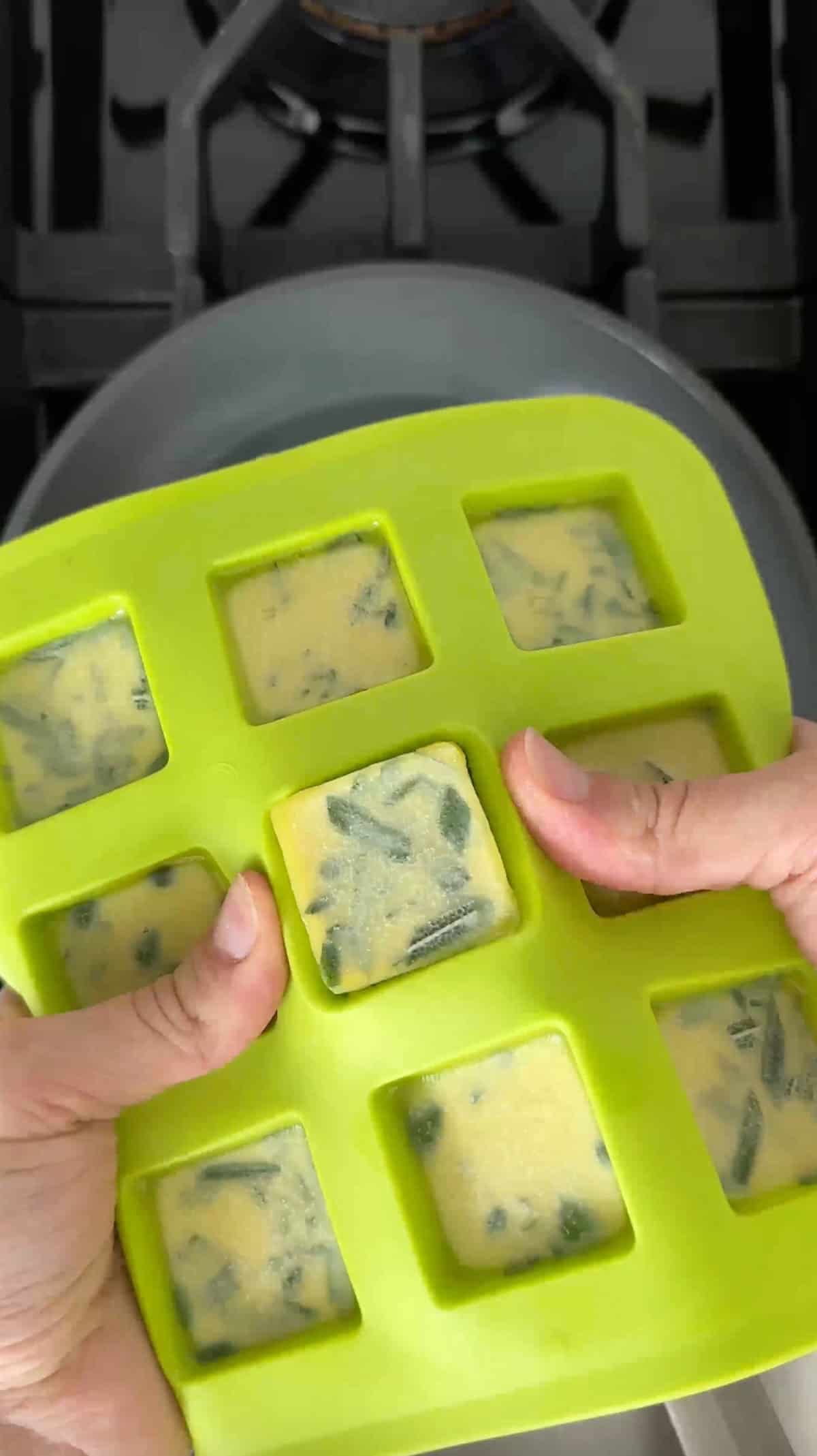 Frozen herb-infused olive oil cubes in a silicone tray.