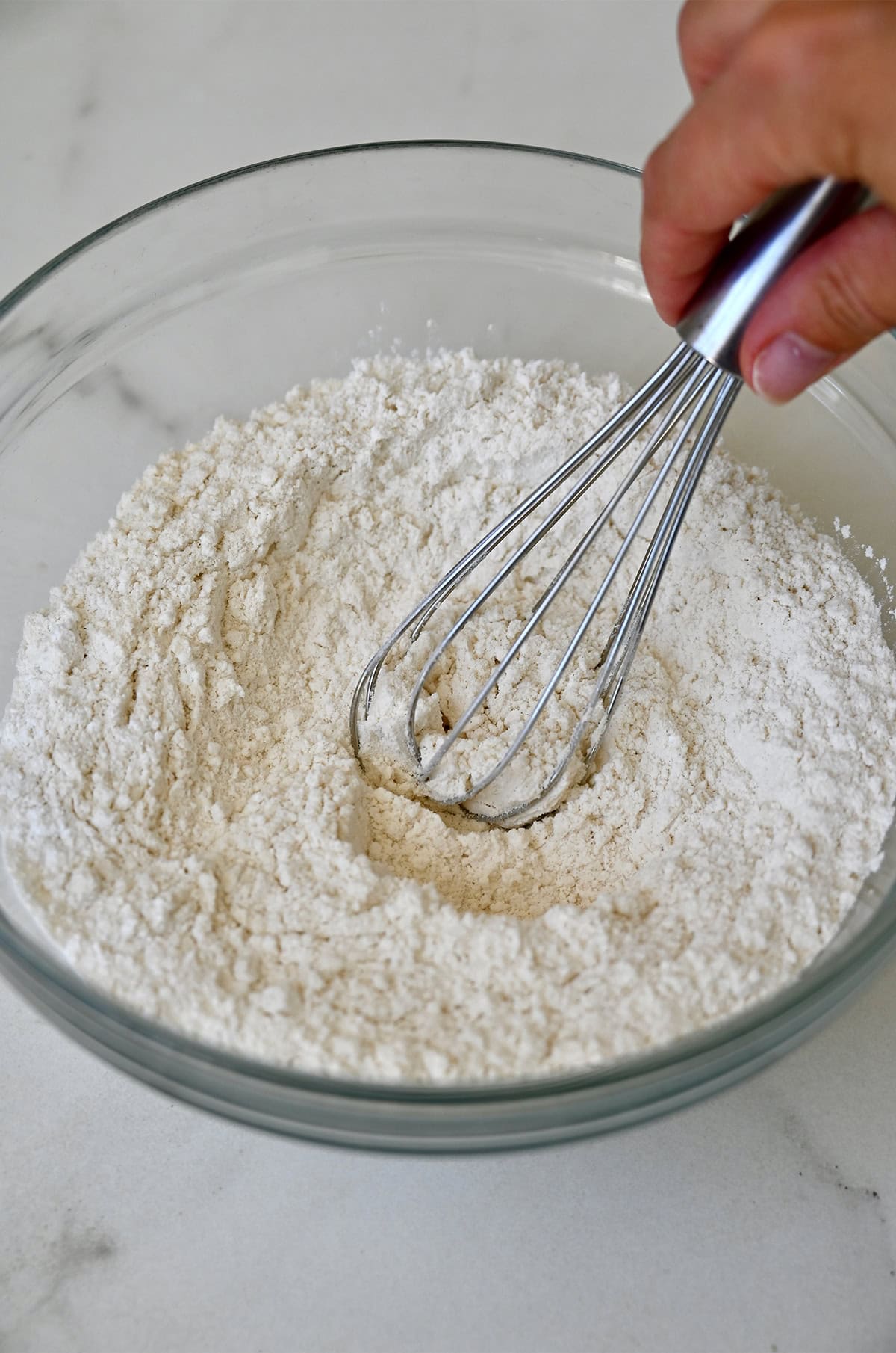 Whisking dry ingredients to make cupcakes in a mixing bowl.