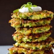 Tall stack of 5-ingredient zucchini fritters topped with sour cream and scallions