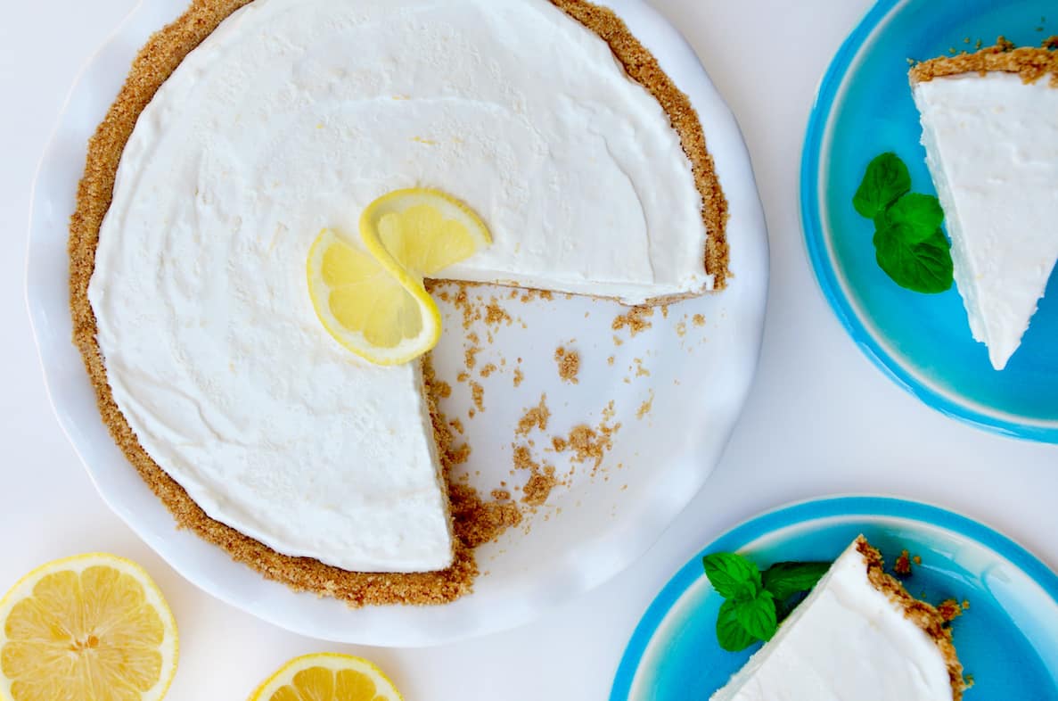 A top-down view of a frozen lemonade pie with a graham cracker crust garnished with a lemon slice.