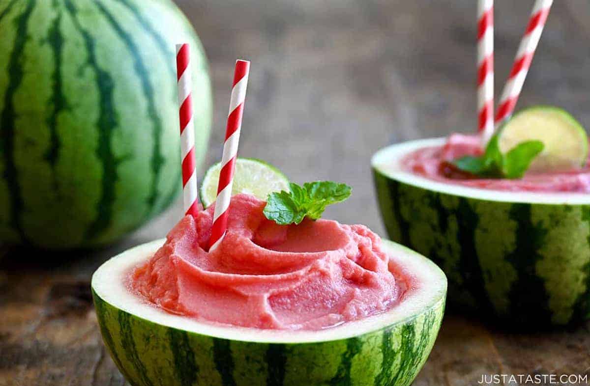 A watermelon bowl containing a watermelon slushy garnished with a fresh mint leaf.