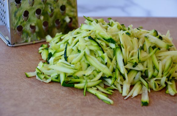 Shredded zucchini on cutting board with box grater