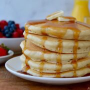 Tall stack of Light and Fluffy Buttermilk Pancakes topped with butter and warm maple syrup