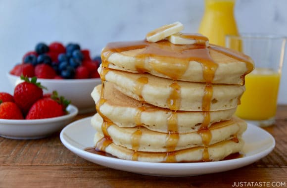 Tall stack of Light and Fluffy Buttermilk Pancakes topped with butter and warm maple syrup
