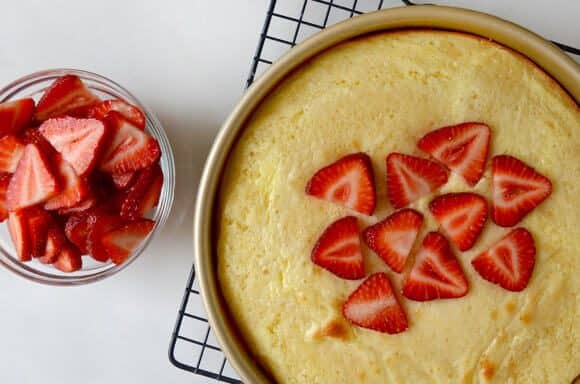 Strawberry cheesecake coffee cake with fresh strawberries on a wire cooling rack.