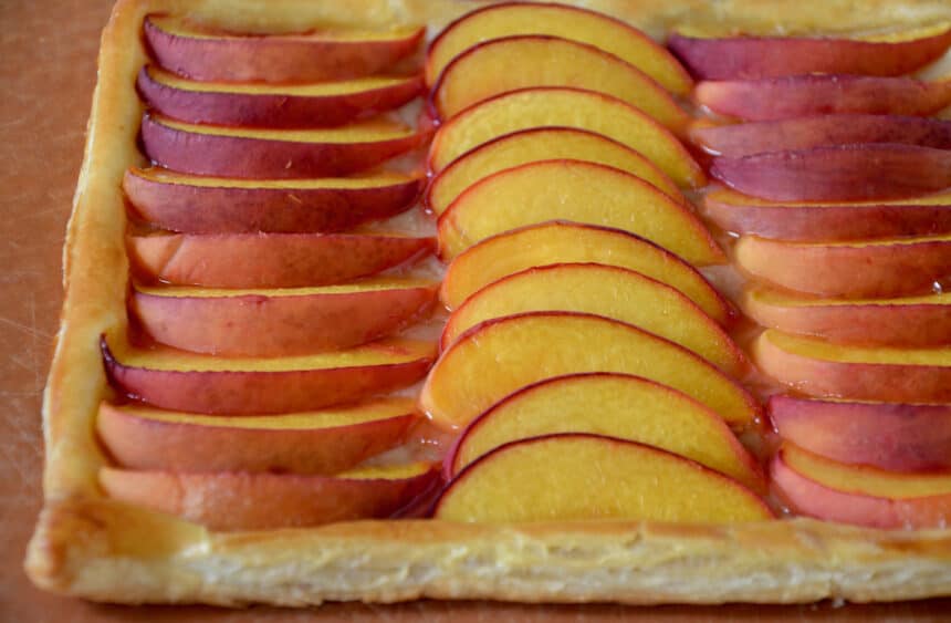 A golden brown pastry with slices of fresh stone fruit.