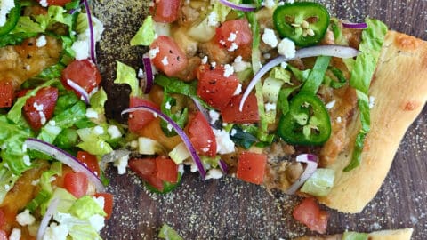 Cheesy taco pizza topped with refried beans, shredded lettuce, jalapeños, cojita cheese and diced tomatoes.