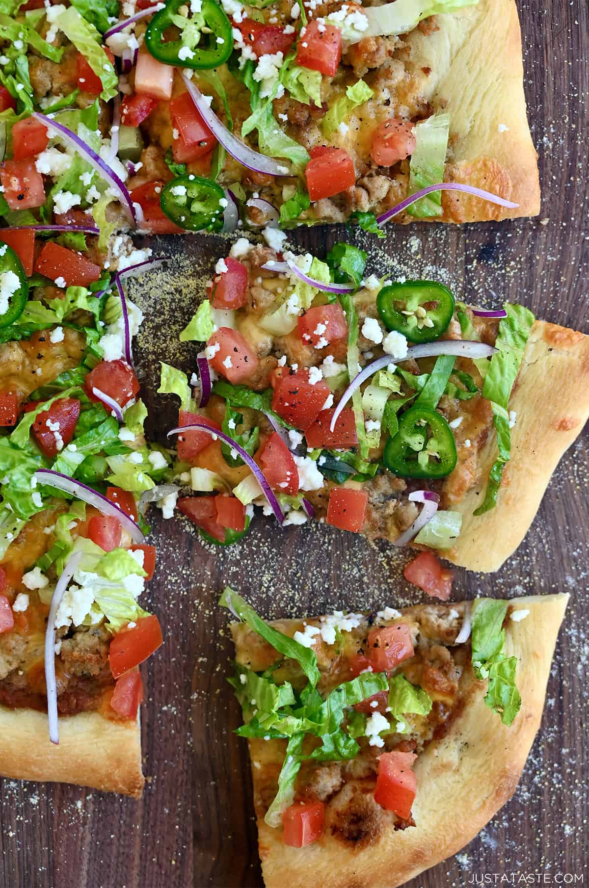 Cheesy taco pizza topped with refried beans, shredded lettuce, jalapeños, cojita cheese and diced tomatoes.