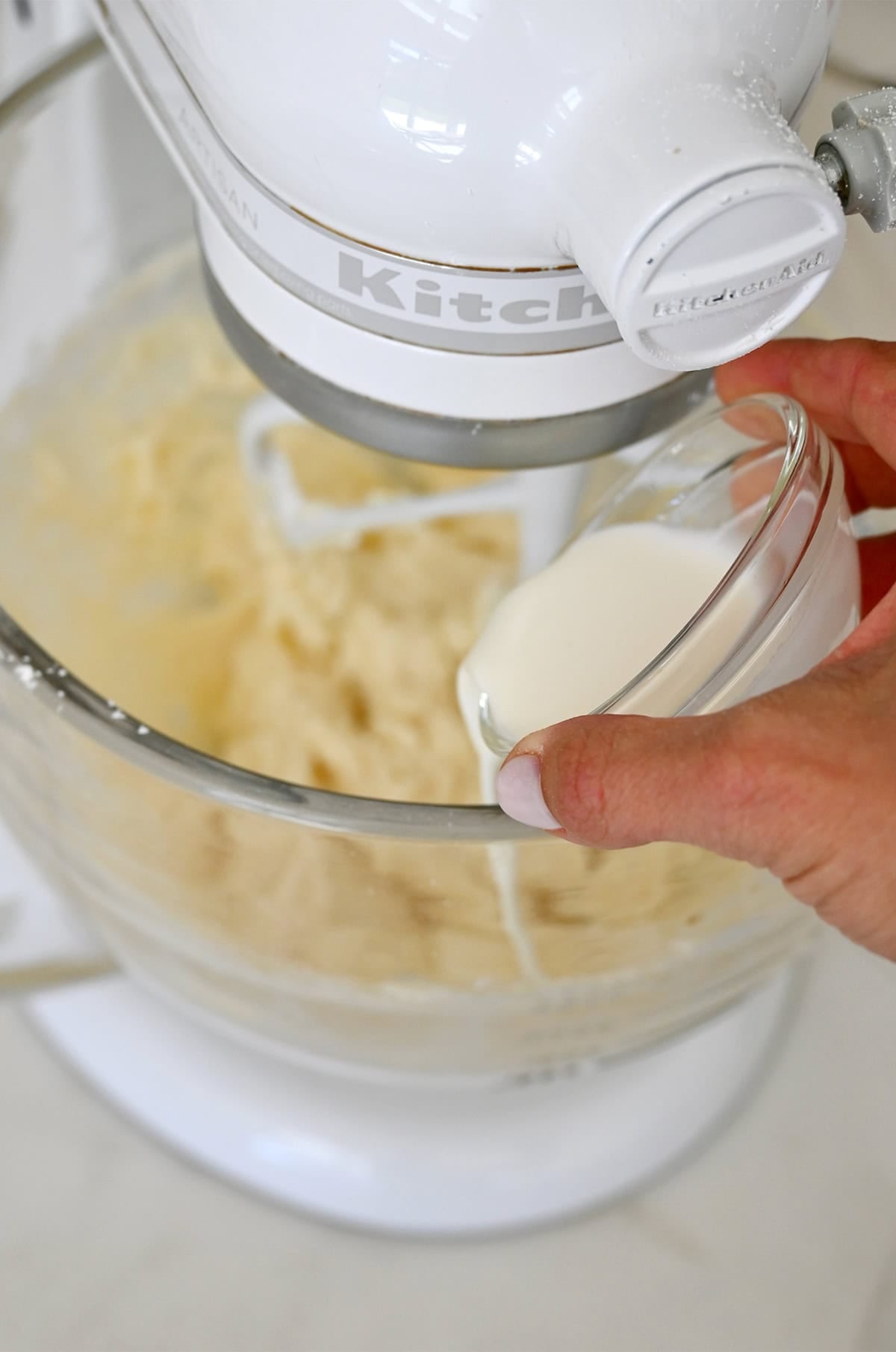 Heaving cream being poured into a mixing bowl to make buttercream frosting.
