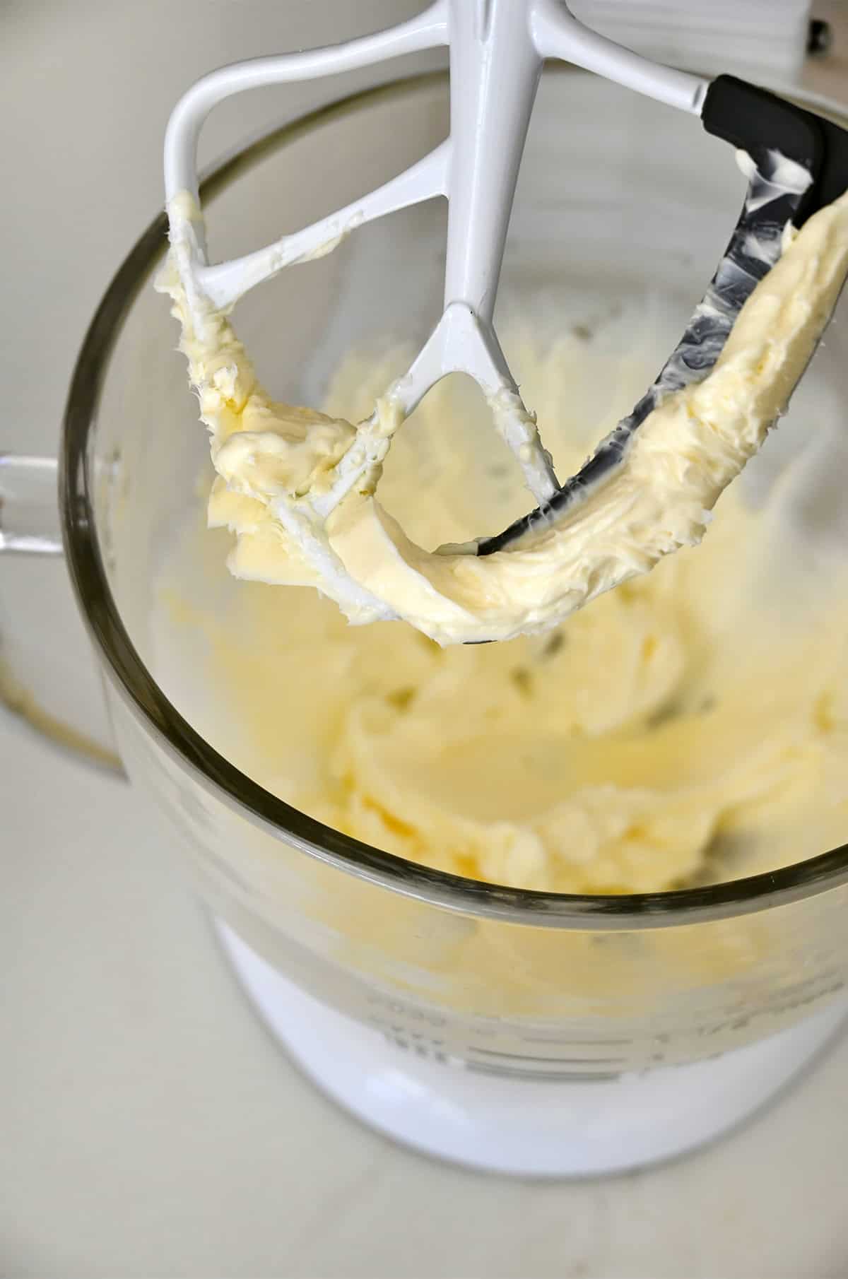 Unsalted butter beaten until pale and creamy in a stand mixer bowl, ready for vanilla buttercream frosting.