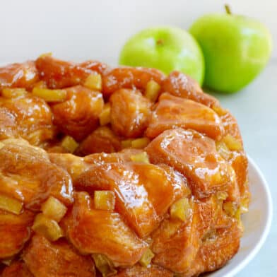 Caramel apple monkey bread with diced Granny Smith apples on a white serving plate.