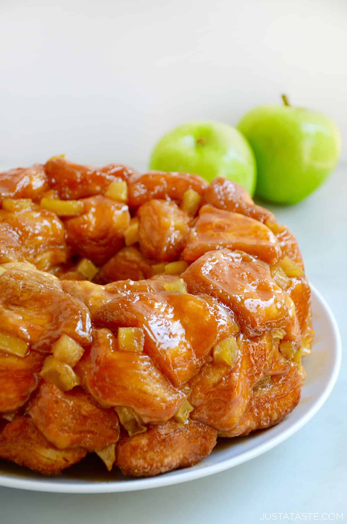 Caramel apple monkey bread with diced Granny Smith apples on a white serving plate.