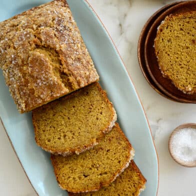 A half-sliced loaf of Pumpkin Banana Bread on a blue serving plate