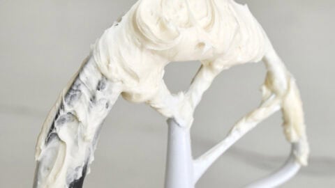 Super-white, fluffy vanilla buttercream frosting on the paddle attachment of a stand mixer.