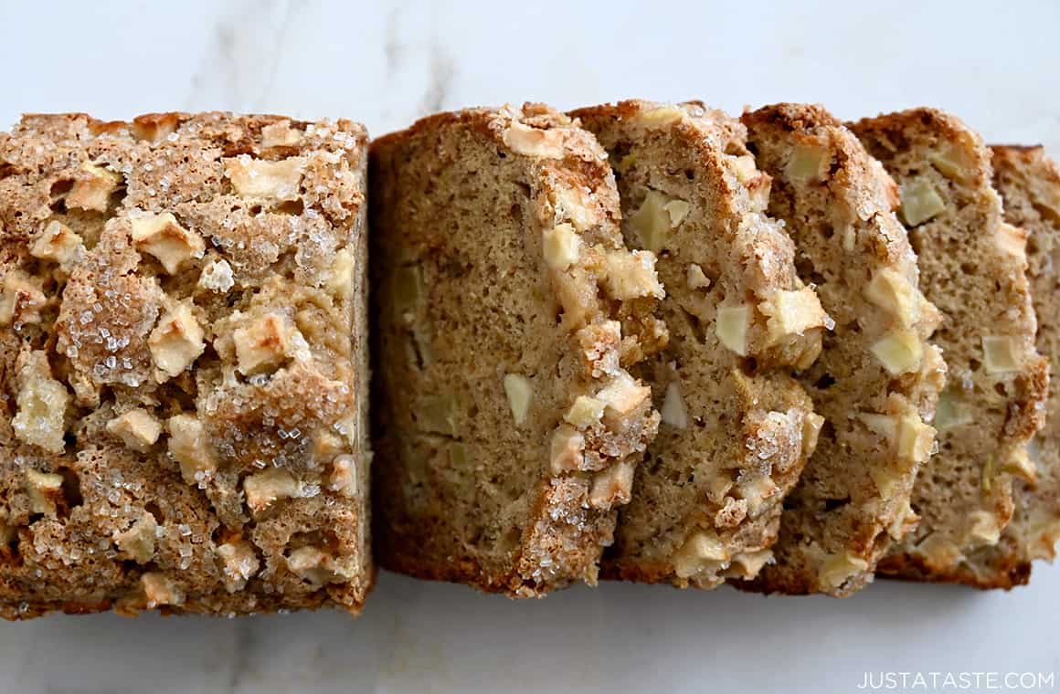 A top-down view of a half-sliced loaf of Apple Cinnamon Banana Bread topped with sanding sugar