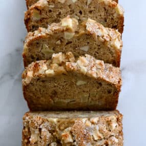 A top-down view of a half-sliced loaf of Apple Cinnamon Banana Bread