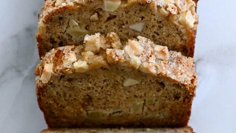 A top-down view of a half-sliced loaf of Apple Cinnamon Banana Bread